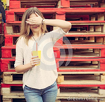 Beautiful blonde girl closes her eyes stands near the wooden racks. Outdoor Stock Photo