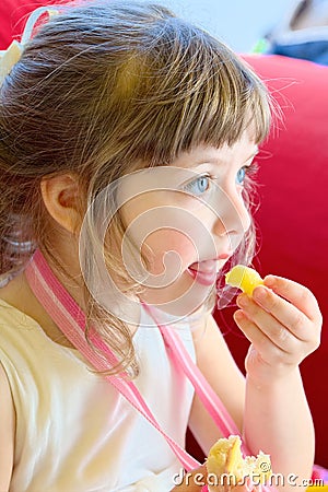 Beautiful blonde girl is going to enjoy a fried potato, sitting on a red couch with a birthday party Stock Photo