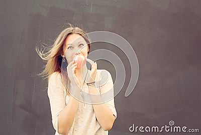 Beautiful blonde girl inflates a red bubble from chewing gum. Outdoor Stock Photo