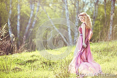 Beautiful blonde girl in pink long dress on a background of nature Stock Photo