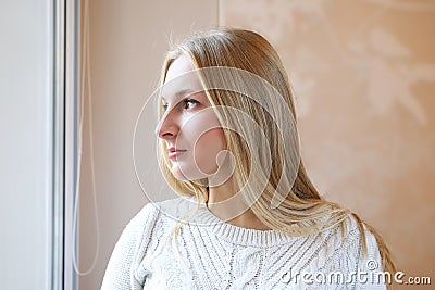 Beautiful blonde girl thoughtfully look out window Stock Photo