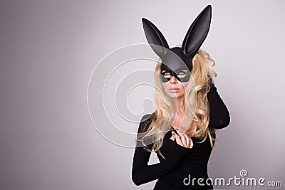 Beautiful blonde-haired young woman in carnival mask ballroom rabbit with long ears sensual in a black dress Stock Photo