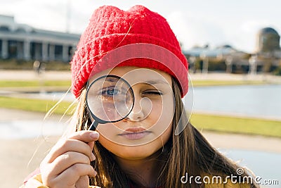 Beautiful blonde teenage girl in a red knitted hat looking through Stock Photo