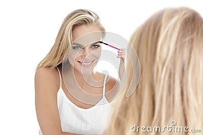 beautiful blonde woman applying mascara in ront of a mirror isolated Stock Photo