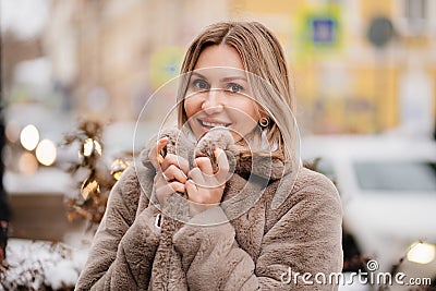 beautiful blonde woman in an artificial fur coat on Christmas streets. Stock Photo