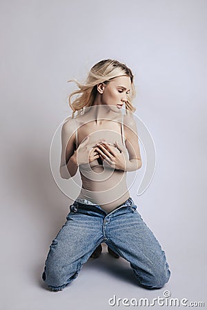 Beautiful blonde woman with long hair is sitting on the floor. Skinny girl with long legs, weight loss, perfect figure Stock Photo