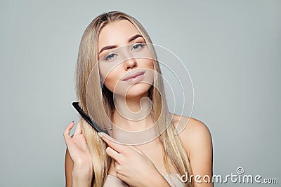 Beautiful blonde woman with long healthy straight hair combing hair. Haircare concept. Girl combs hair Stock Photo