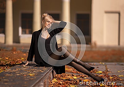 Beautiful blonde woman with perfect legs in pantyhose posing outdoor at the autumn street Stock Photo