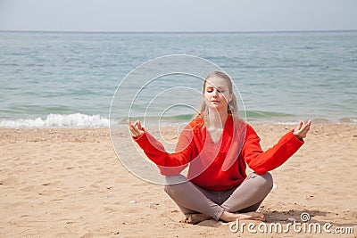 Beautiful blonde woman sits yoga on the beach by the sea Stock Photo