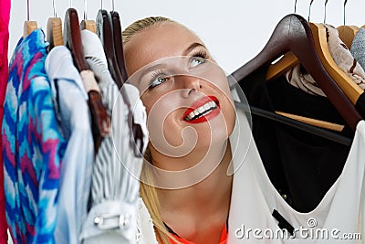 Beautiful blonde woman standing inside wardrobe rack Stock Photo