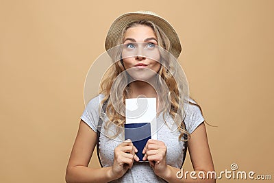 Beautiful blonde woman wearing summer clothes posing with passport with tickets over beige background Stock Photo