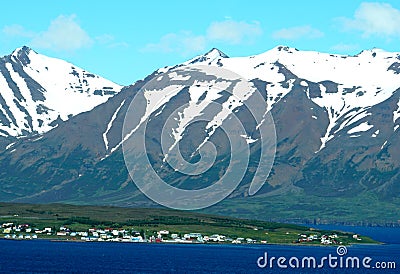 Beautiful blue fjord overlooking partially covered snowy mountain in the summer near Hofn, Iceland Stock Photo