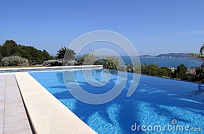 Beautiful blue fresh infinity swimming pool in a villa in sunny Spain with sea views Stock Photo