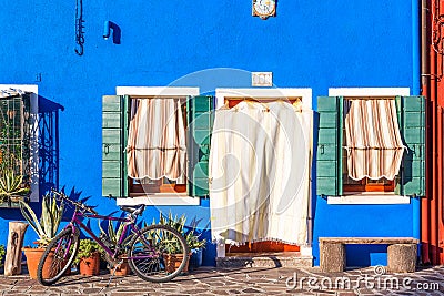 Beautiful blue house with a bicycle, plants and bench. Colorful houses in Burano island near Venice, Italy. Stock Photo