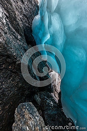 Beautiful blue ice next to water flowing over large stones. Stock Photo