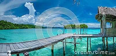 Beautiful Blue Lagoone with some Bamboo Huts, Kordiris Homestay, Palmtree in Front, Gam Island, West Papuan, Raja Ampat Stock Photo