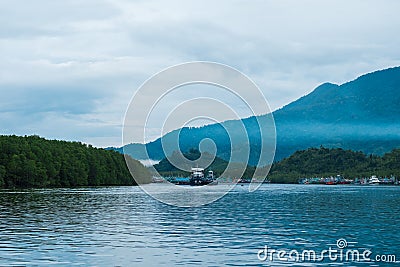 beautiful blue sea, fisherman village on coast and have big mountain, fog are bacgkround. this image for landscape,seascape and n Stock Photo