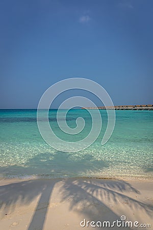 Beautiful blue water beach in a tropical paradise, with bungalows in the background in Maldives Stock Photo