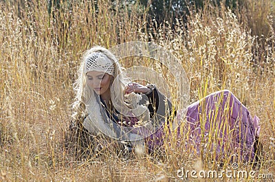 Beautiful bohemian blonde woman lying in field of grass Stock Photo