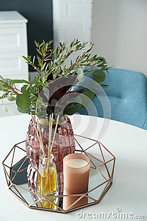 Beautiful bouquet with eucalyptus branches, candle and aromatic reed air freshener on white table indoors. Interior elements Stock Photo