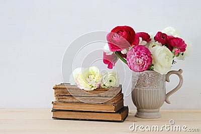 Beautiful bouquet of flowers in the vase next to old books Stock Photo