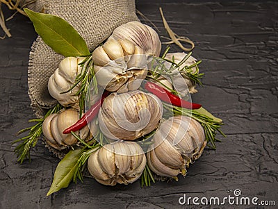 A beautiful bouquet of fresh garlic with red pepper and Bay leaves . Wrapped in coarse matting and tied with Linden bast Stock Photo