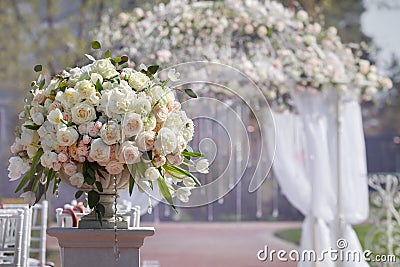 Beautiful bouquet of roses in a vase on a background of a wedding arch. Beautiful set up for the wedding ceremony. Stock Photo