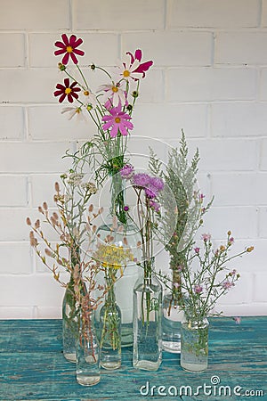 Beautiful bouquet of wildflowers in a variety of bottles on a white background. Beige furry spikes, gray wormwood, bright daisies Stock Photo