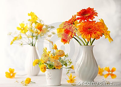 Beautiful bouquet of red and yellow flowers in white vase on wooden table, front view. Autumn still life with flowers Stock Photo