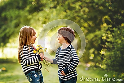 Beautiful boy and girl in a park, boy giving flowers to the girl Stock Photo