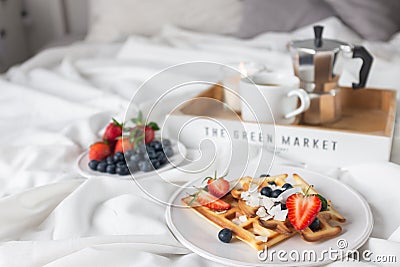 Beautiful breakfast in bed: Viennese Belgian waffles decorated with berries, a plate with strawberries and blueberries Stock Photo