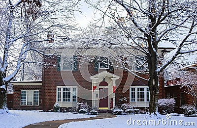 Beautiful brick house with bay windows with Christmas tree showing through and decorated pillars and sled on porch in snow framed Stock Photo