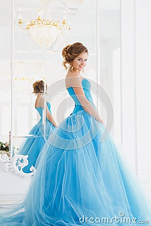 Beautiful bride in gorgeous blue dress Cinderella style near mirror Stock Photo