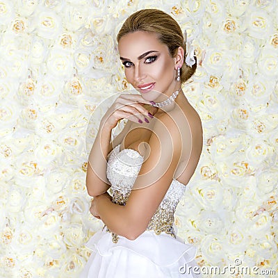 Beautiful bride in a stunning wedding dress with lace. Beauty young woman on a background of roses - Image Stock Photo