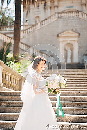 beautiful bride in tender wedding dress with bridal bouquet on the stairs of the Nativity of the Blessed Virgin Mary Stock Photo