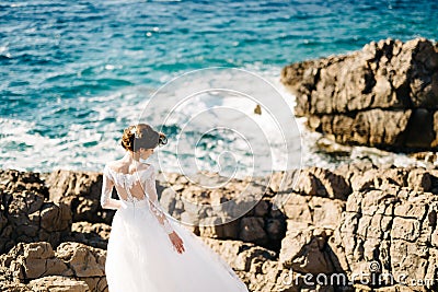 Beautiful bride in tender wedding dress on the rocky beach of the Mamula island Stock Photo