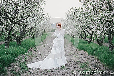 Beautiful bride in a vintage wedding dress posing in a blooming apple garden. Spring mood Stock Photo