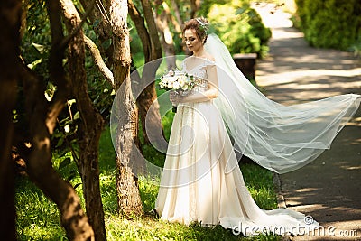 Beautiful bride walking in the park. Wedding veil disperse of wind. Beauty portrait of a bride around amazing nature Stock Photo
