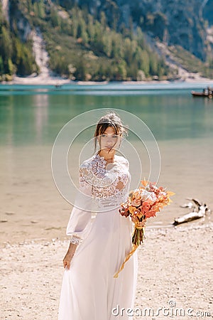 Beautiful bride in a white dress with sleeves and lace, with a yellow autumn bouquet of dried flowers and peony roses Stock Photo