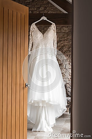 Beautiful brides wedding dress hanging in barns from wooden beams Stock Photo