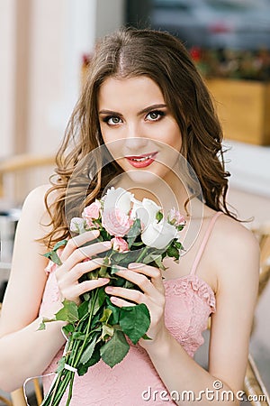 Beautiful brown-haired young girl with a bouquet of roses, professional makeup and styling. Romantic and gentle image. Stock Photo