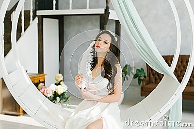 A beautiful brunette bride holds a pen in her hands and touches herself on the face with a pen Stock Photo