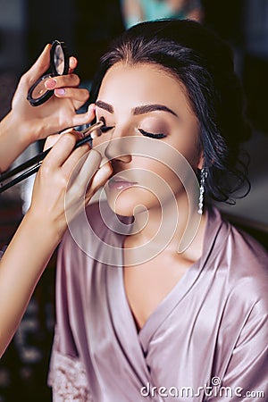 A beautiful bride makeup artist applies makeup. Wedding morning of the bride Stock Photo