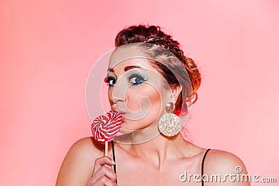 Beautiful brunette girl with blue makeup, pigtails and a sexy black top posing against a red background with a heart-shaped Stock Photo