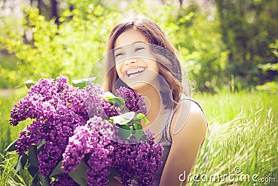 Beautiful brunette girl with a lilac flowers relaxing and enjoying life in nature. Outdoor shot. Copyspace Stock Photo