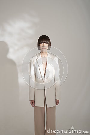 Beautiful brunette with graphic bob haircut wear beige fashion pantsuit Stock Photo