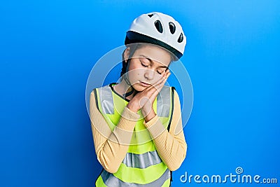 Beautiful brunette little girl wearing bike helmet and reflective vest sleeping tired dreaming and posing with hands together Stock Photo