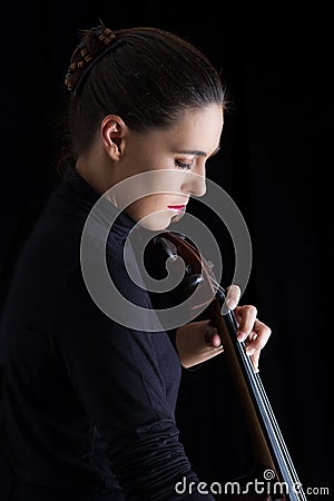 Beautiful brunette playing cello with selective light in black d Stock Photo