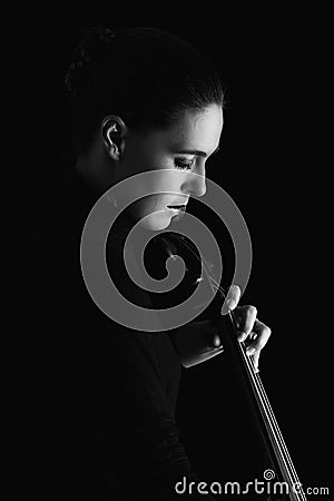 Beautiful brunette playing cello with selective light in black d Stock Photo