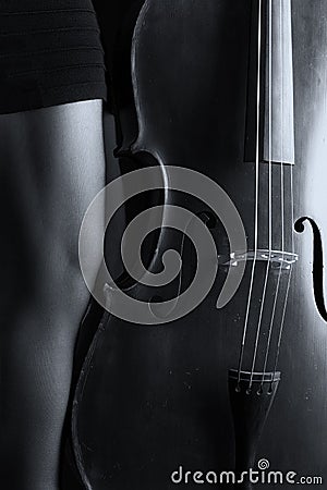 Beautiful brunette playing cello with selective light in black d Stock Photo